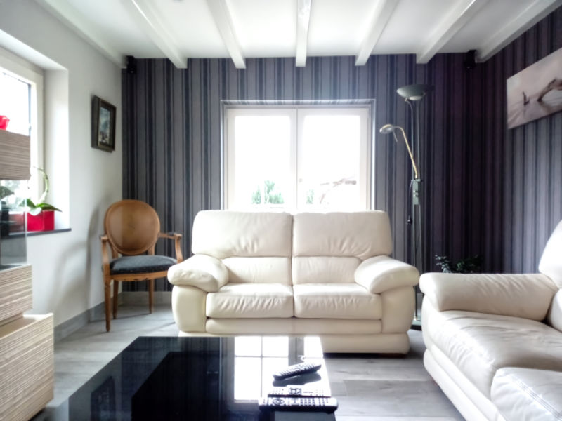 vue d'ensemble d'un salon avec fauteuil en cuir blanc et papier peint en nuance de gris ave des bandes bleues
